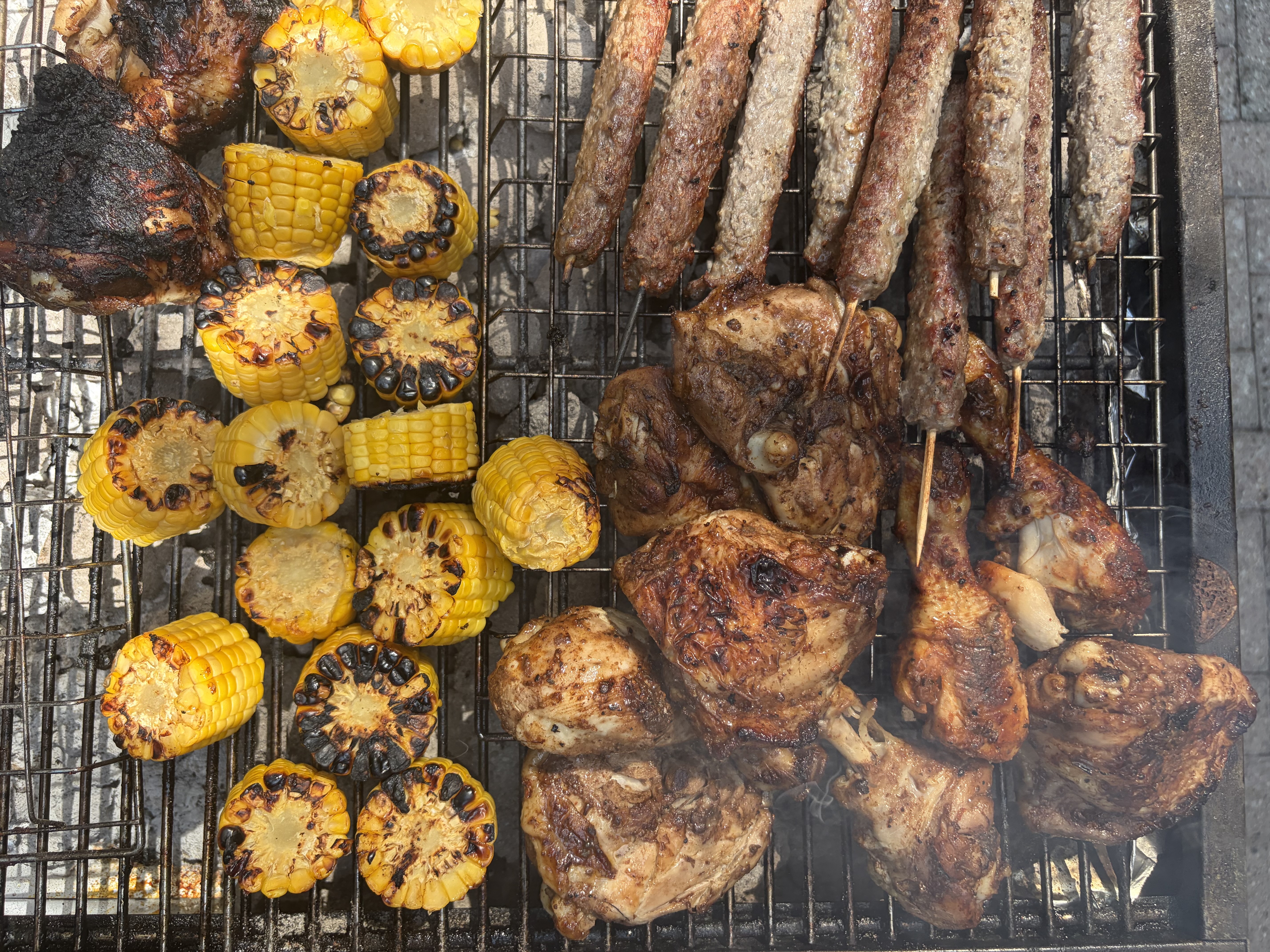 Grilled corn, chicken and kofta cooking on a barbecue grill