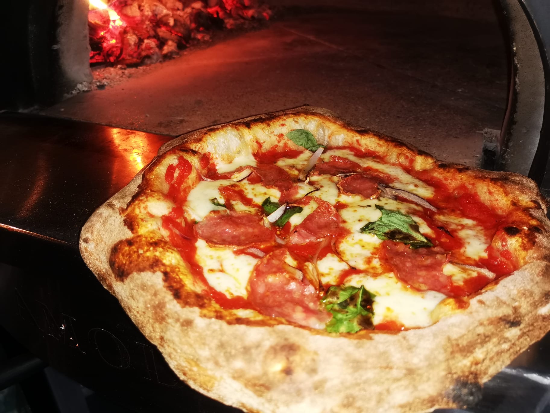 Freshly baked salami pizza inside a wood-fired oven