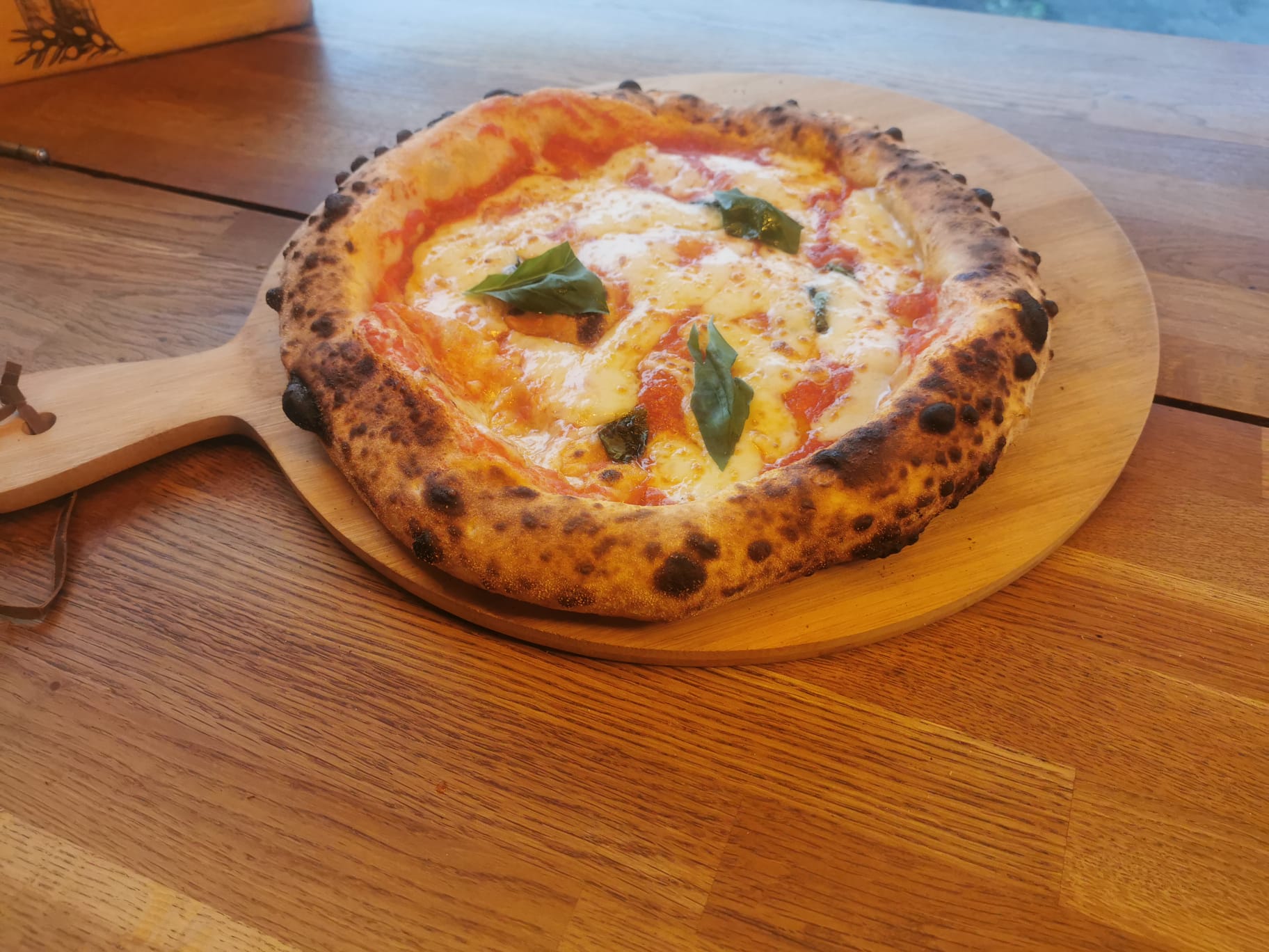 Wood-fired Margherita pizza with basil on a wooden board